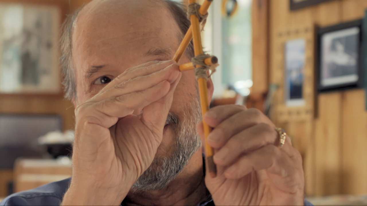 a man with a beard looking through 3 pencils